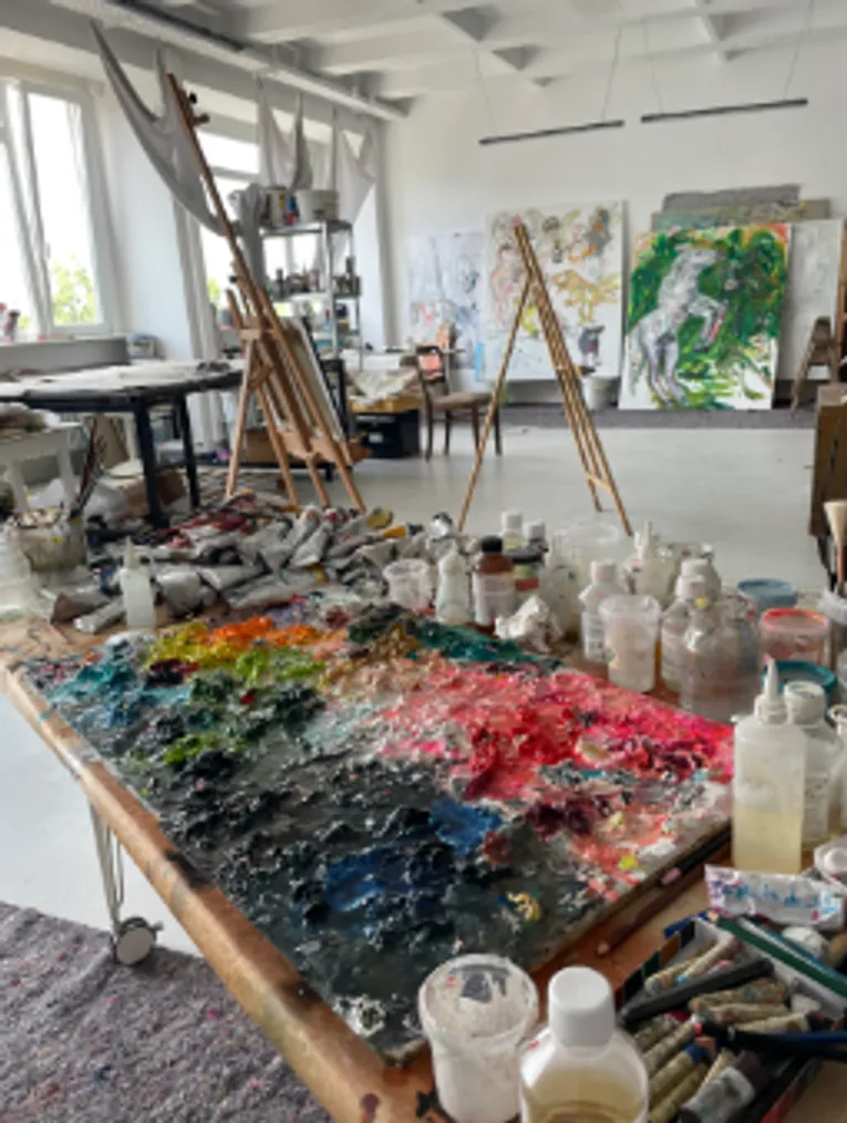 Art studio with easels and paints on table.