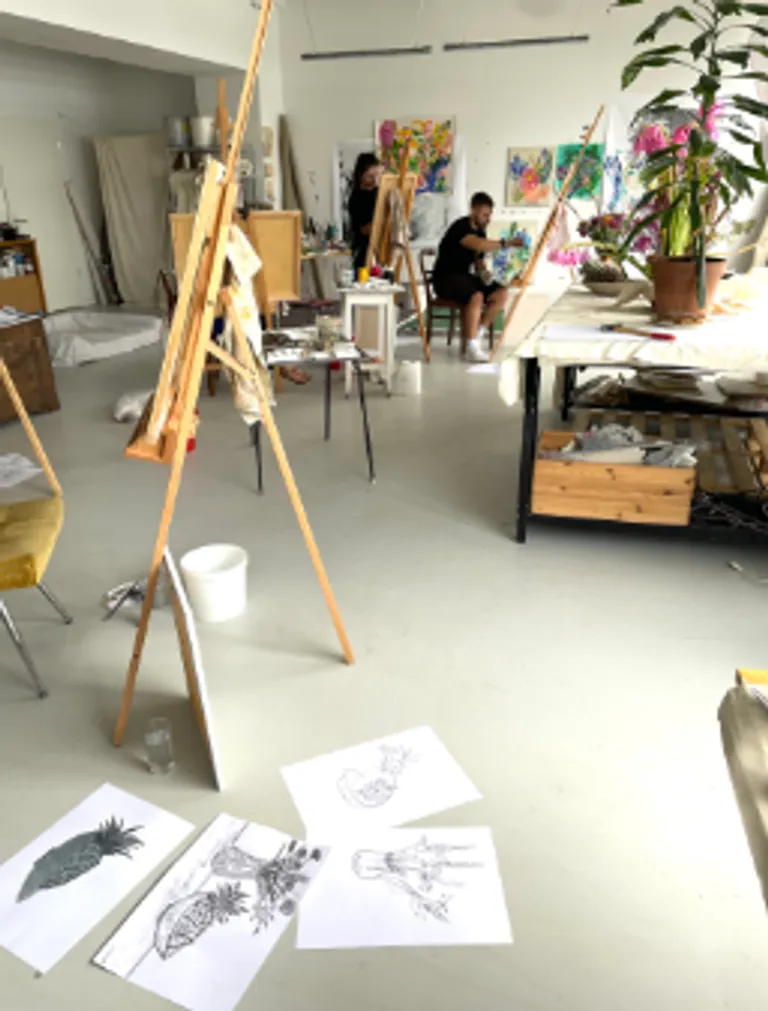 Artists working in a studio with canvases.