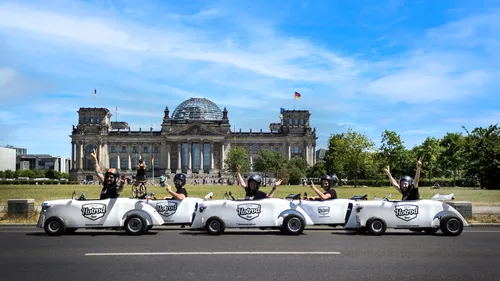 Gruppe in kleinen Autos winkend, Reichstag Hintergrund.