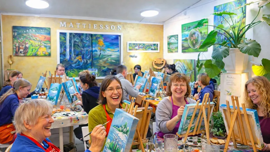 Group painting class; people happily painting canvases.