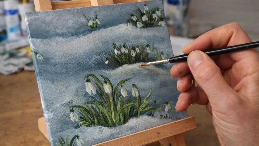 Hand painting snowdrops on canvas with brush.