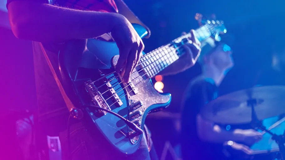 Bassist plays guitar on stage, drummer visible.