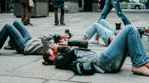 Photographers lying on pavement taking photos.