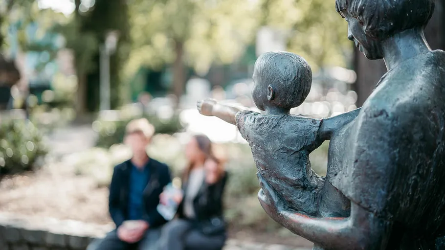 Statue of woman and child in park.