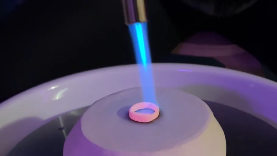 Ring being heated by blowtorch on platform.