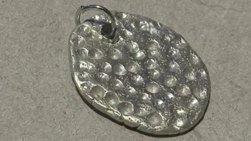 Silver pendant on a textured surface.