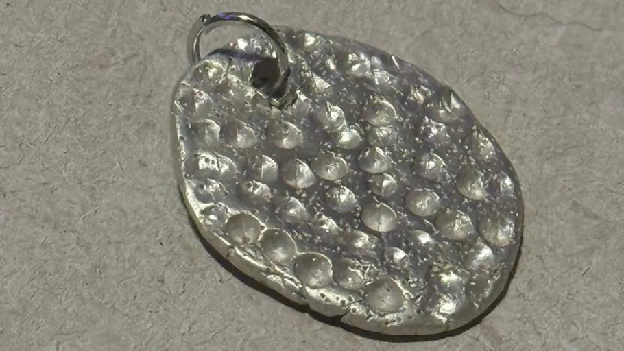Silver pendant on a textured surface.