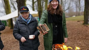 Two women enjoying outdoor fire in a park.
