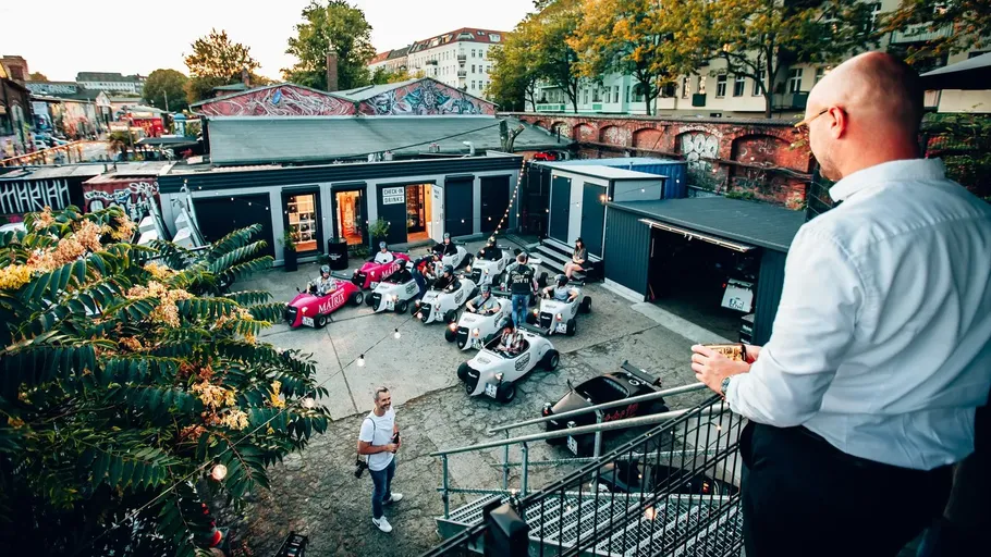 Group driving go-karts in urban courtyard.