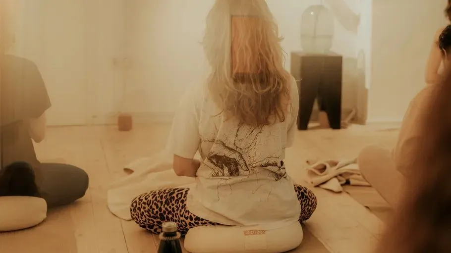People meditating on cushions in a warm room.