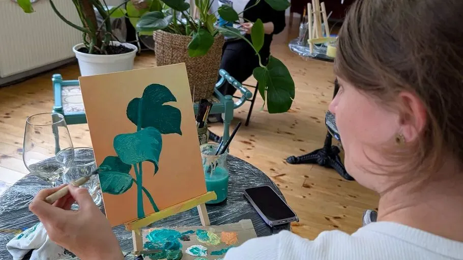 Person painting leaves on easel indoors.