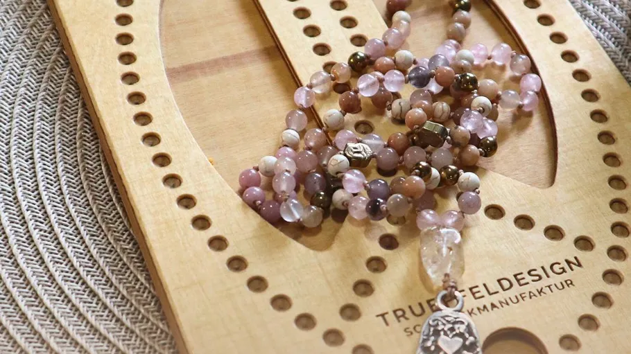Beaded necklace on wooden tool, textured background.