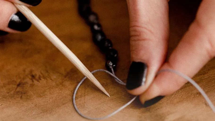 Hand threading beads with wooden needle