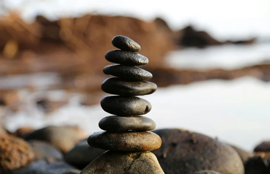 Stacked stones balanced on rocky shore.