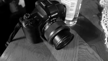 Camera and bottle on wooden table.