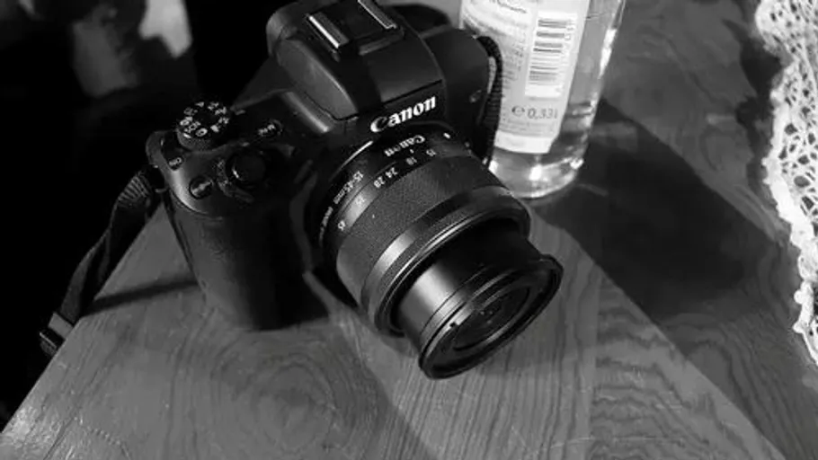 Kamera und Flasche auf Holztisch.