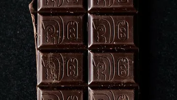 Chocolate bar with ancient symbols, black background.