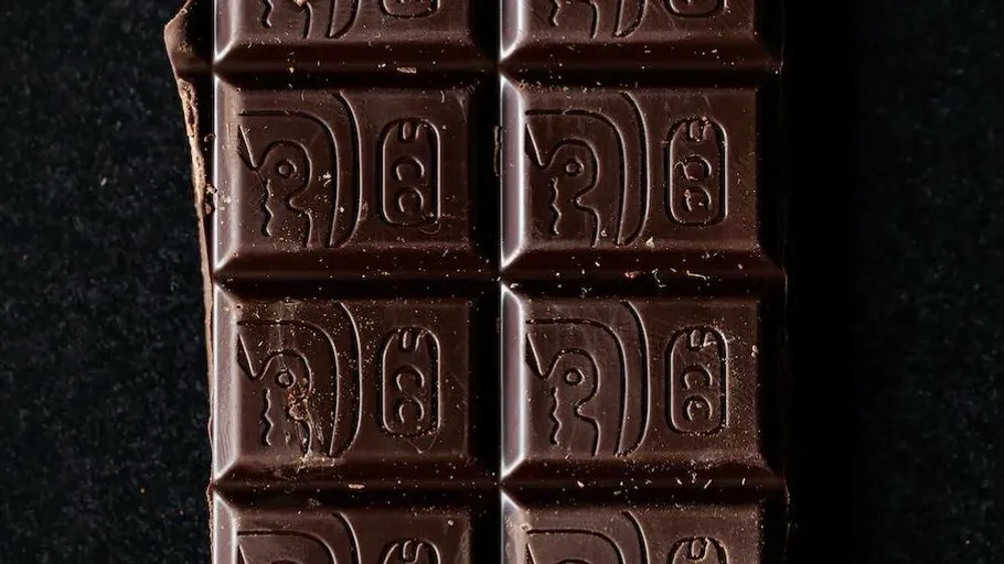 Schokoladentafel mit antiken Symbolen, schwarzer Hintergrund.