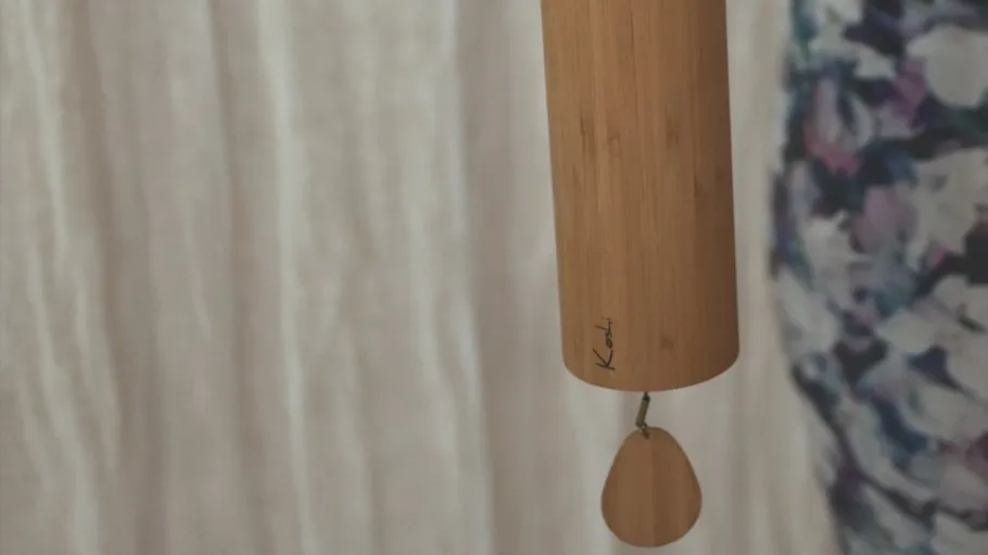 Bamboo wind chime hanging indoors, floral background.
