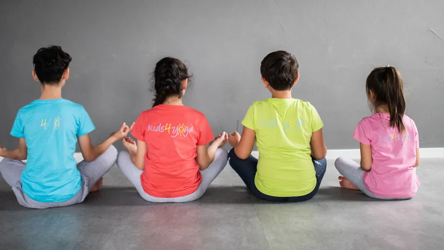 Vier Kinder meditieren in bunten T-Shirts.