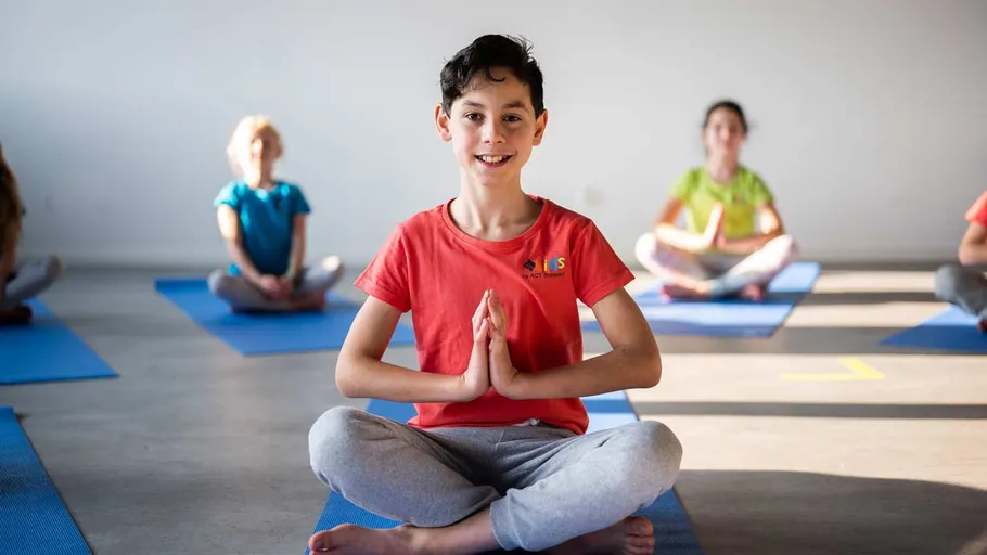 Child practicing yoga in a group setting.