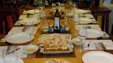 Tisch gedeckt mit Geschirr, Wein und Oliven.