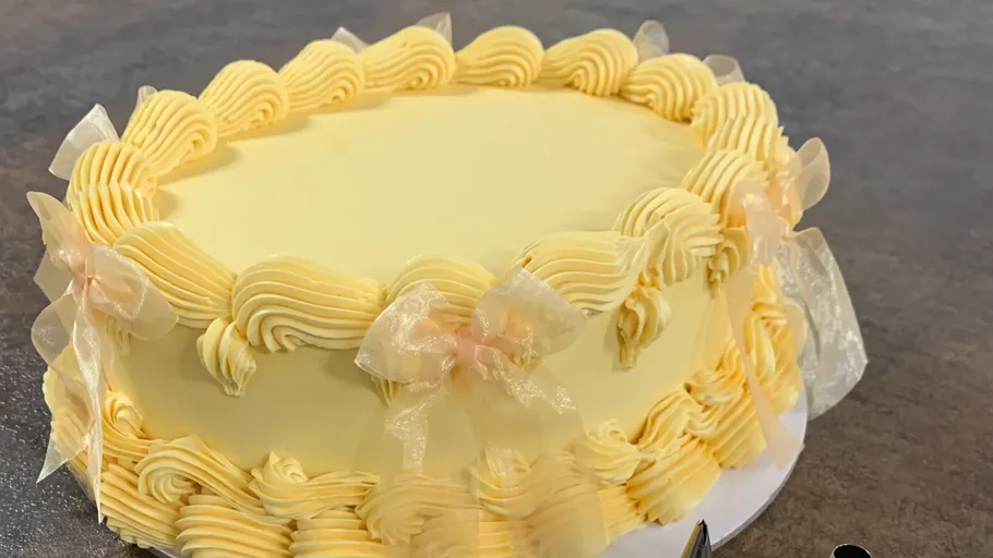 Yellow cake with decorative ribbons on table.