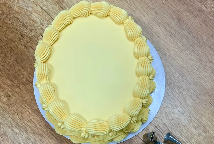 Yellow cake with piped frosting on table.