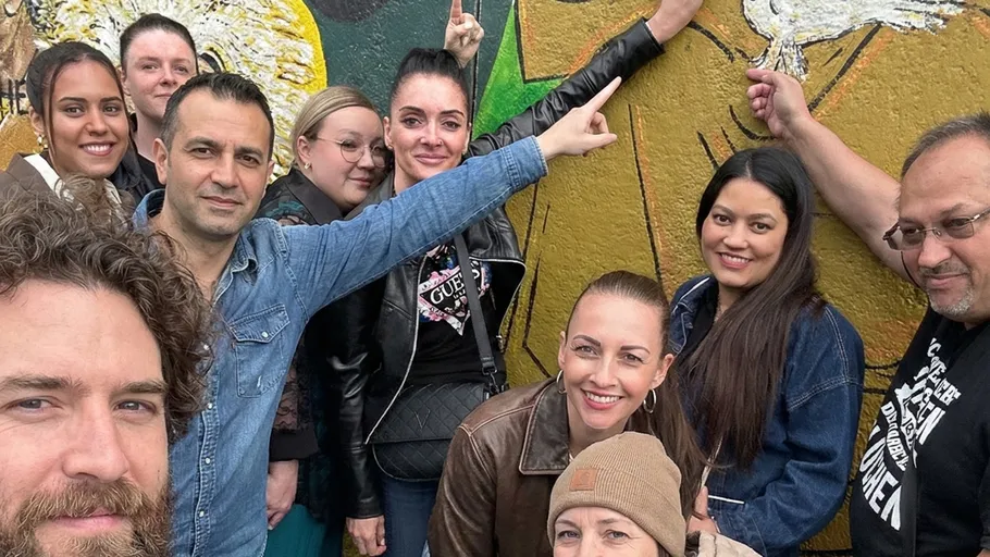 Gruppe von Menschen posiert an bemalter Wand.