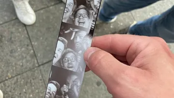 Hand holding photo strip with smiling faces.