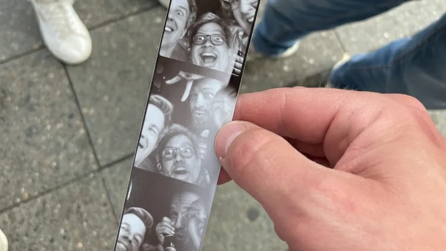 Hand hält Fotostreifen mit lachenden Gesichtern.