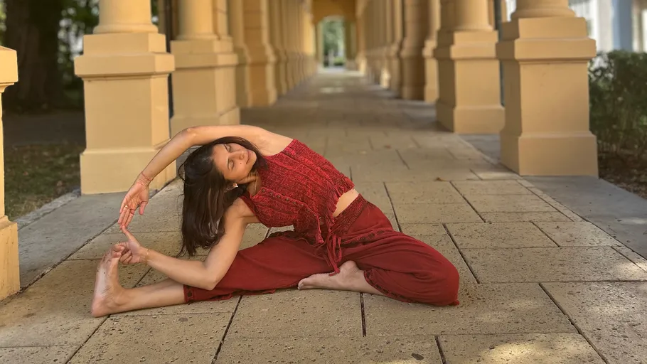 Woman practicing yoga in a columned hallway.