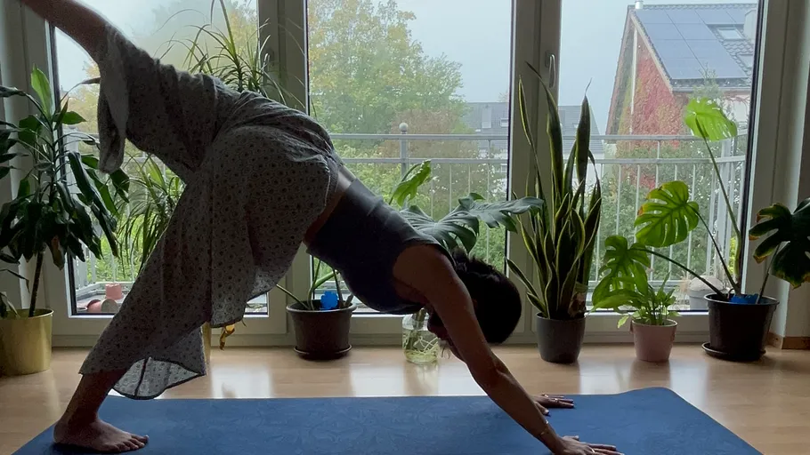 Woman doing yoga in a plant-filled room.