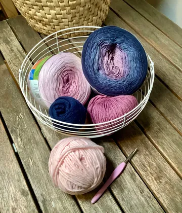 Garnknäuel im Korb auf Holztisch.
