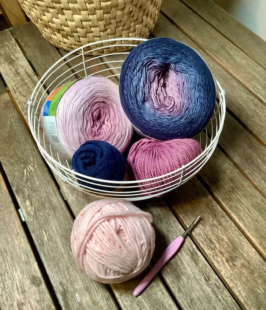 Yarn balls in basket on wooden table.