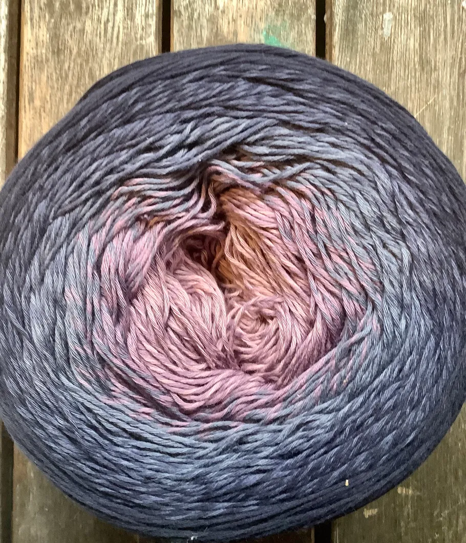 Gradient yarn ball on wooden surface.