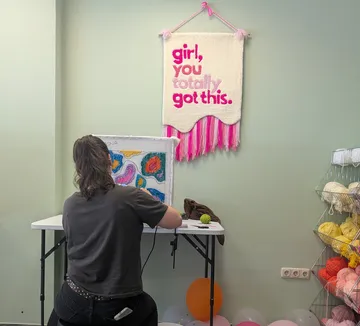 Person tufting colorful fabric in art studio.