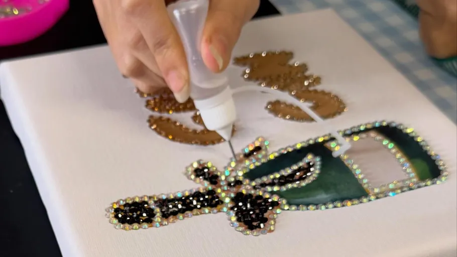 Hand trägt Kleber auf Diamantgemäldeleinwand auf.