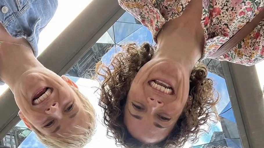 Two women smiling, photographed from below.