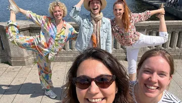 Group posing joyfully by waterfront railing.