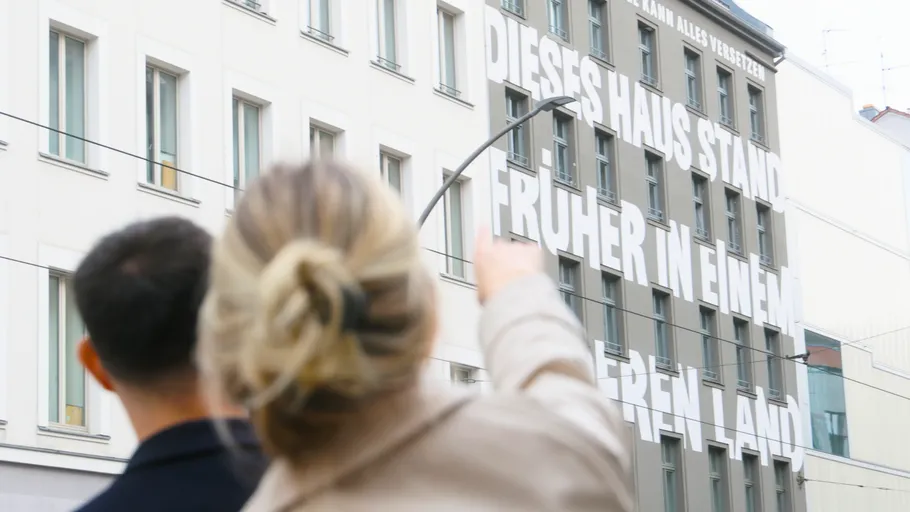 Personen zeigen auf Gebäude mit großem Text.