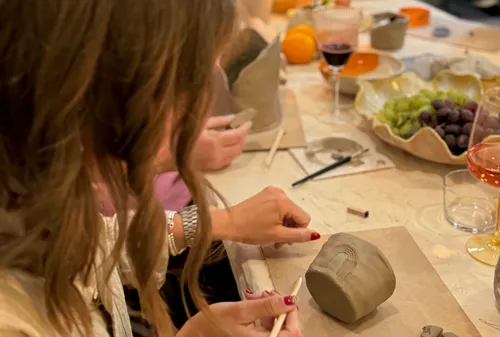 Woman sculpting clay object at table.