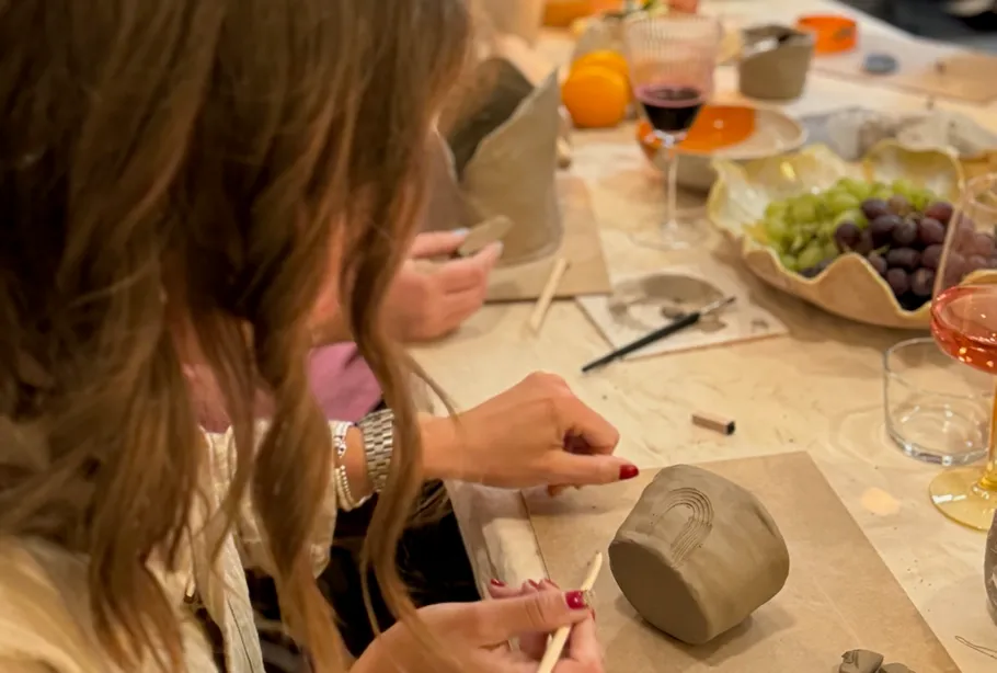 Woman sculpting clay object at table.