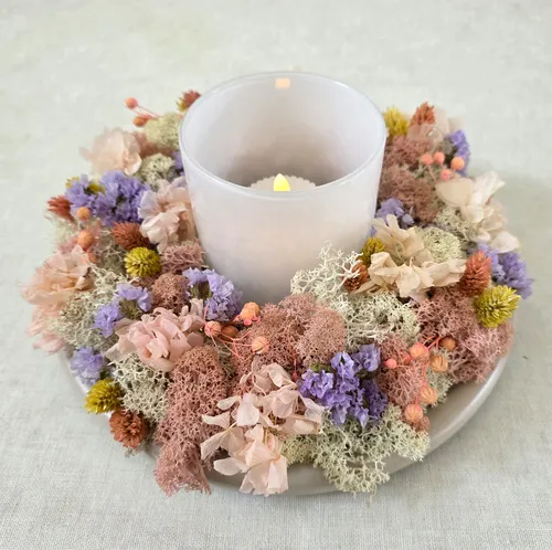 Candle surrounded by colorful dried flowers.
