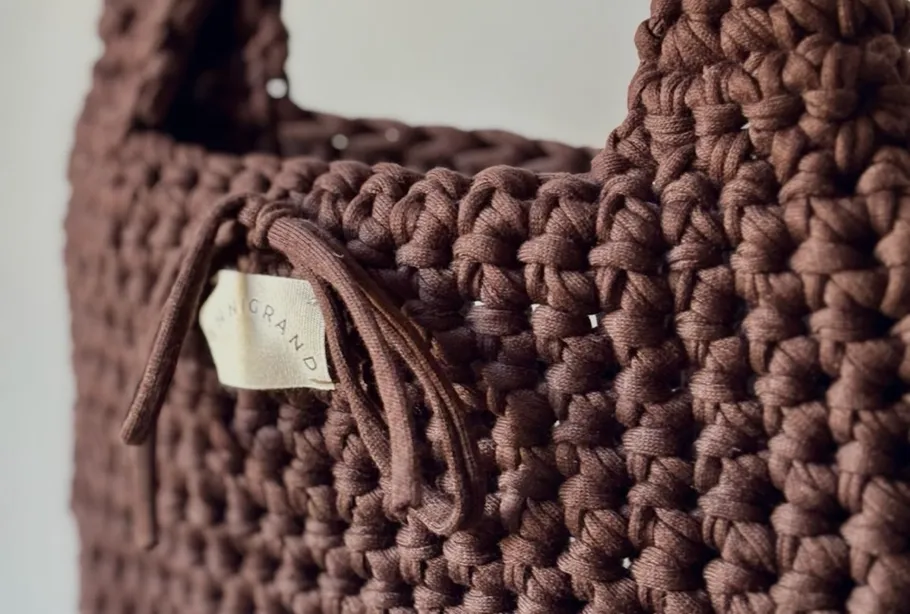 Brown woven bag with handle and label.