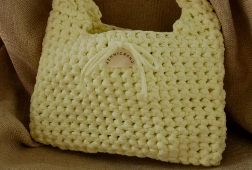Yellow crochet bag with label on fabric.