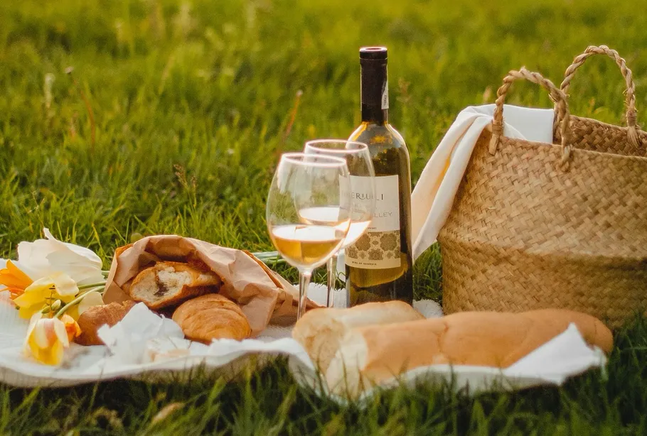 Picknick mit Wein auf Wiese.