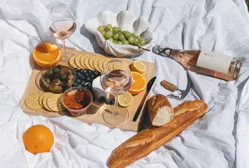 Picnic with wine, bread, fruits, and cheese.