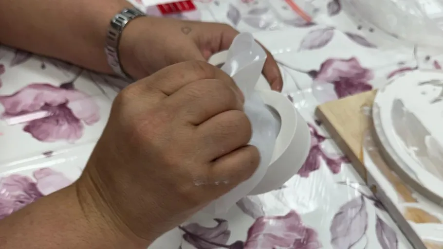 Hands peeling rubber mold on floral tablecloth.