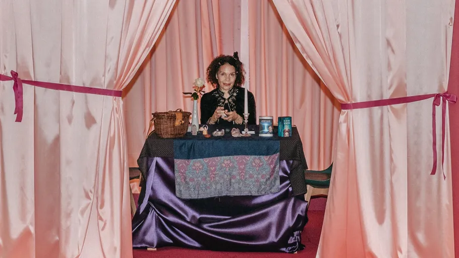 Person sits at table with candles behind curtains.